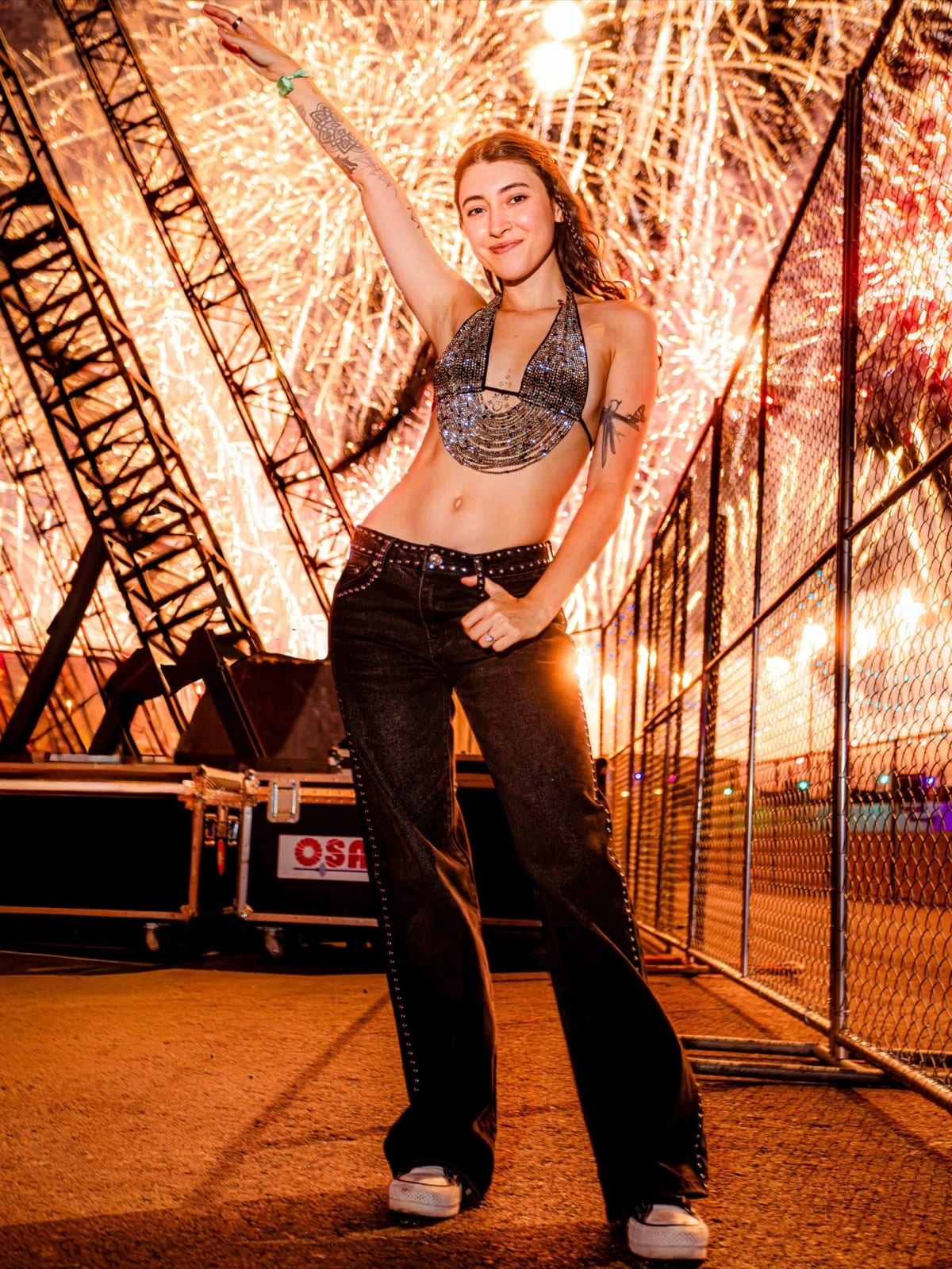 Level Up posing backstage with fireworks lighting up the sky behind her